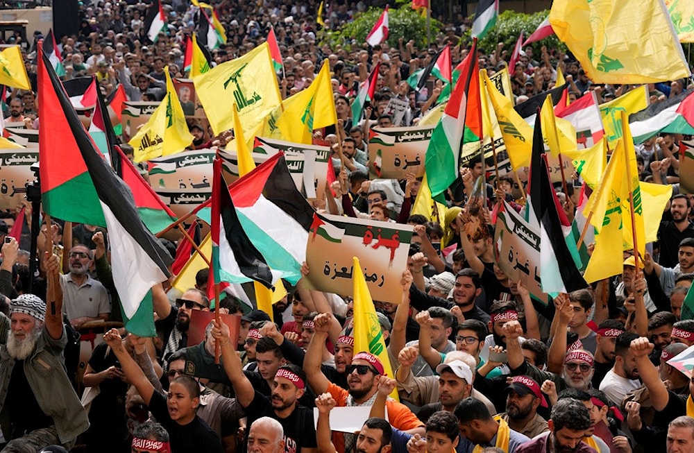 Hezbollah supporters wave Lebanese, Palestinian, and Hezbollah flags, as they hold pro-Gaza placards during a protest to show their solidarity with the Palestinians, in the southern suburb of Beirut, Lebanon, Friday, Oct. 13, 2023 (AP)