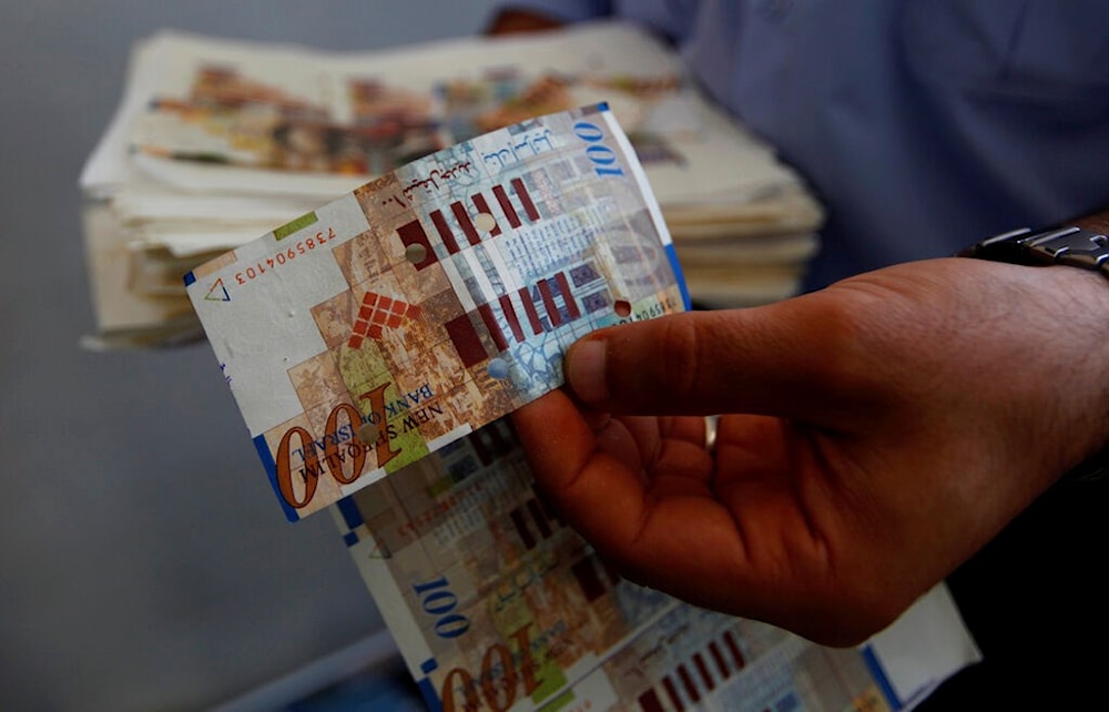 An Israeli policeman displays counterfeit 100 Israeli Shekel bills,  July 7, 2013 (AP)