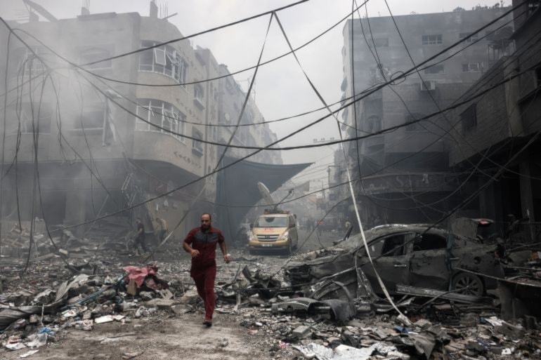 A Palestinian runs through the debris of an Israeli air strike that hit the Jabalia refugee camp on October 9, 2023 (AFP)