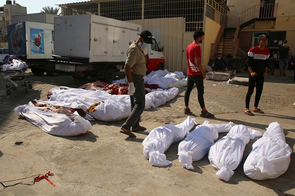 Palestinians stand by the bodies of people killed in the Israeli bombardment of the Gaza Strip in front of the morgue in Deir al Balah City, Gaza Strip, Wednesday, Nov. 1, 2023. (AP Photo/Abdel Kareem Hana)