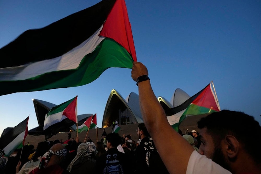 Palestinian supporters wave flags as they march to the Sydney Opera House in Sydney, October 9, 2023 (AP)