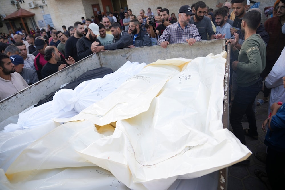 Palestinians stand around their relatives martyred in the Israeli bombardment of the Gaza Strip, in front of the morgue in Deir al Balah, November 11, 2023 (AP)
