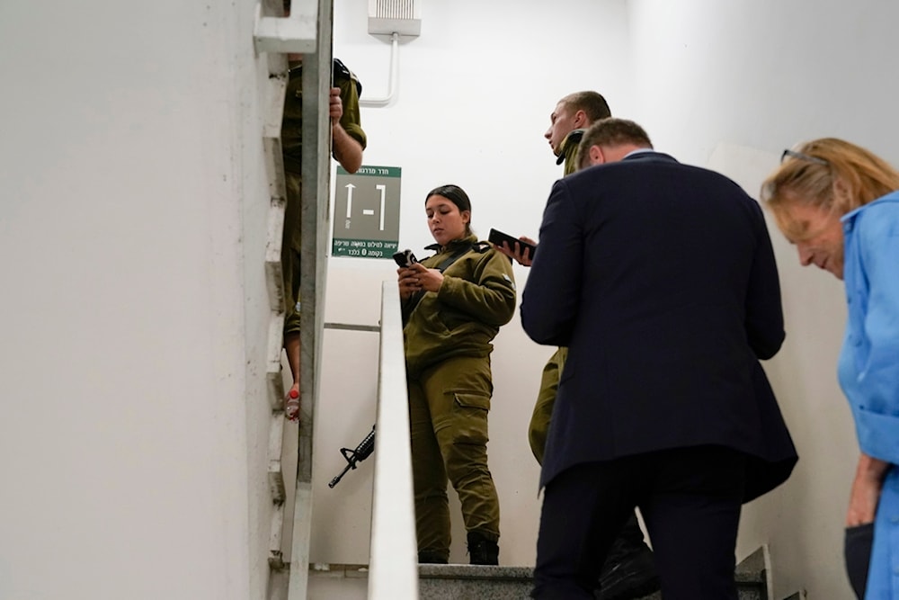 Members of the press and Israeli soldiers take shelter in a stairwell inside at The Kirya, which houses the Israeli Ministry of Security, October 16, 2023, in 'Tel Aviv', occupied Palestine (AP)