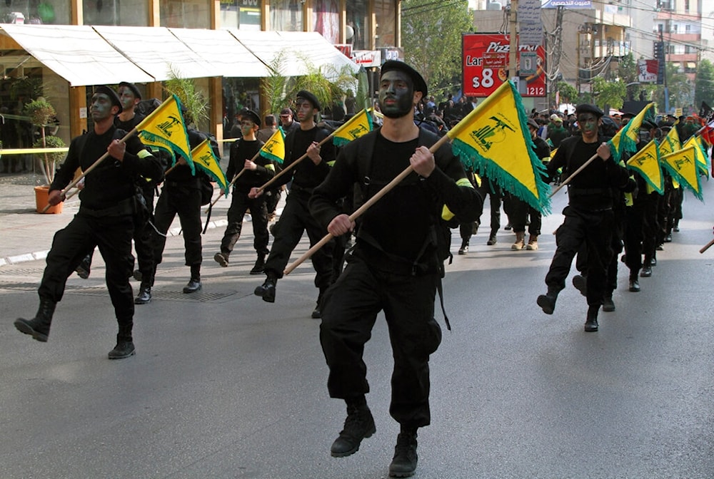 Hezbollah fighters hold their party flags, as they parade during a rally to mark the 13th day of Ashoura, in the southern market town of Nabatiyeh, Lebanon, Sunday, Nov. 17, 2013 (AP)