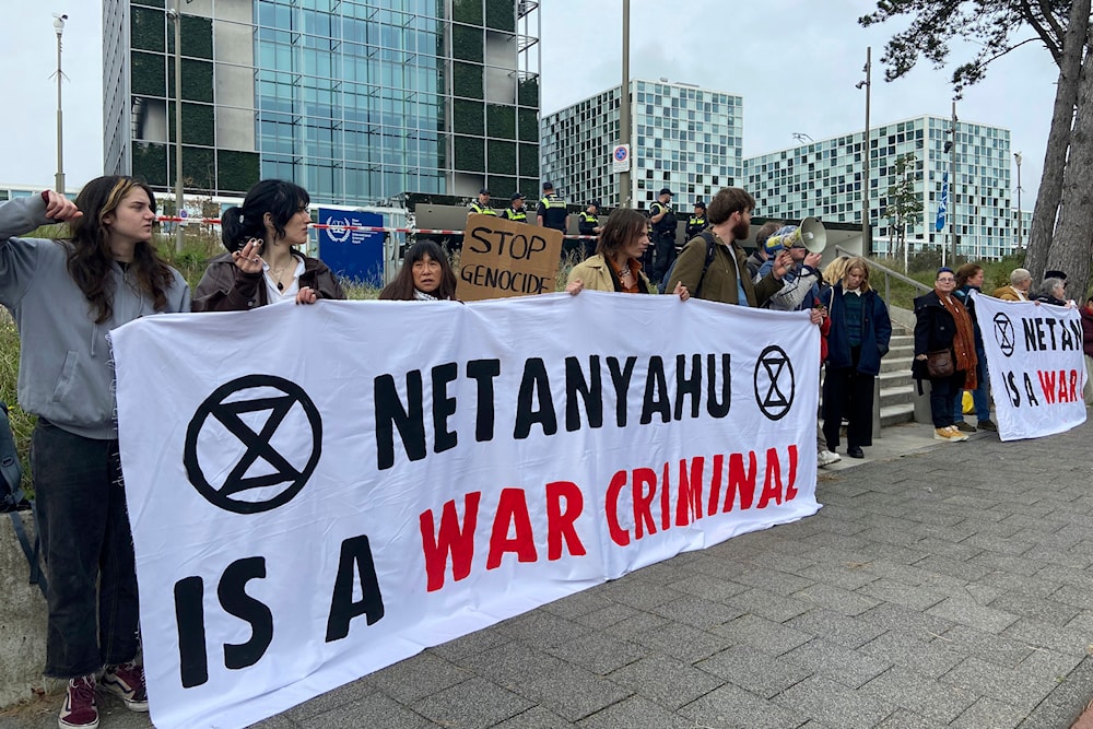Activists hold up a banner denouncing Israeli Prime Minister Benjamin Netanyahu for Israel’s actions at the entrance of the International Criminal Court in The Hague on Oct. 23, 2023. (AP)