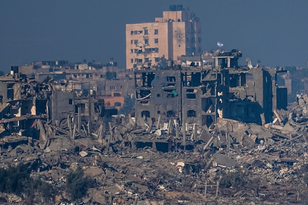 Israeli flags put up on destroyed residential buildings in the Gaza Strip, as seen from southern occupied Palestine, November 18, 2023 (AP)
