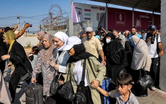 Palestinians with dual citizenship walk through a gate to enter the Rafah border crossing to Egypt in the southern Gaza Strip on November 1, 2023 (AFP)