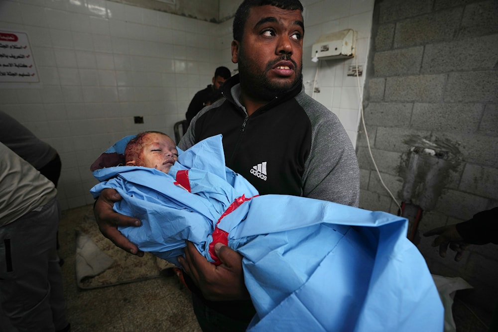 Palestinian relative carries the body of child Fawze Musleh, killed in the Israeli bombardment of the Gaza Strip at the morgue of al Aqsa Hospital in Deir al Balah, Gaza Strip, Sunday, Nov. 19, 2023. (AP)