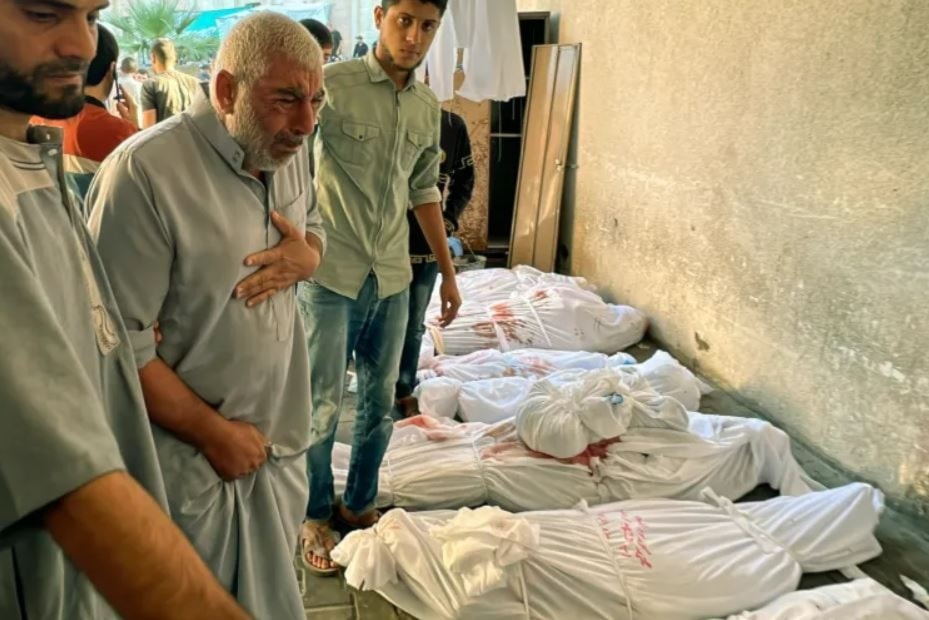 A Palestinian man finds the body of a relative among those lined up following Israeli air raids on the Jabalia refugee camp, at the Indonesian hospital, northern Gaza Strip, November 18, 2023 (AP)