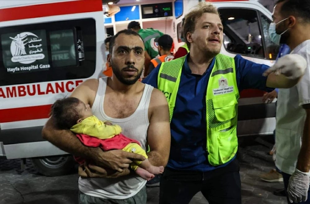 A man brings an injured baby into Al-Shifa Hospital in Gaza following an Israeli airstrike on October 12. (AFP via Getty Images)