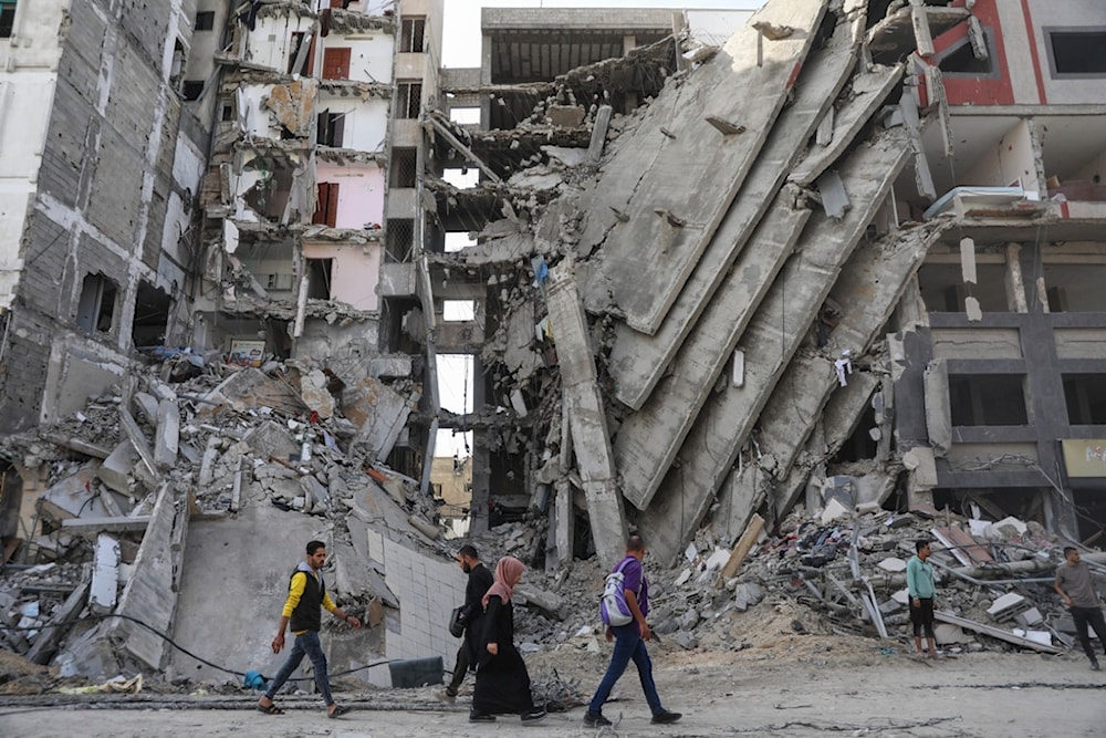 Palestinians walk through destruction in Gaza City on Friday, Nov. 24, 2023, as the temporary ceasefire between Israel and Hamas took effect (AP Photo/Mohammed Hajjar)