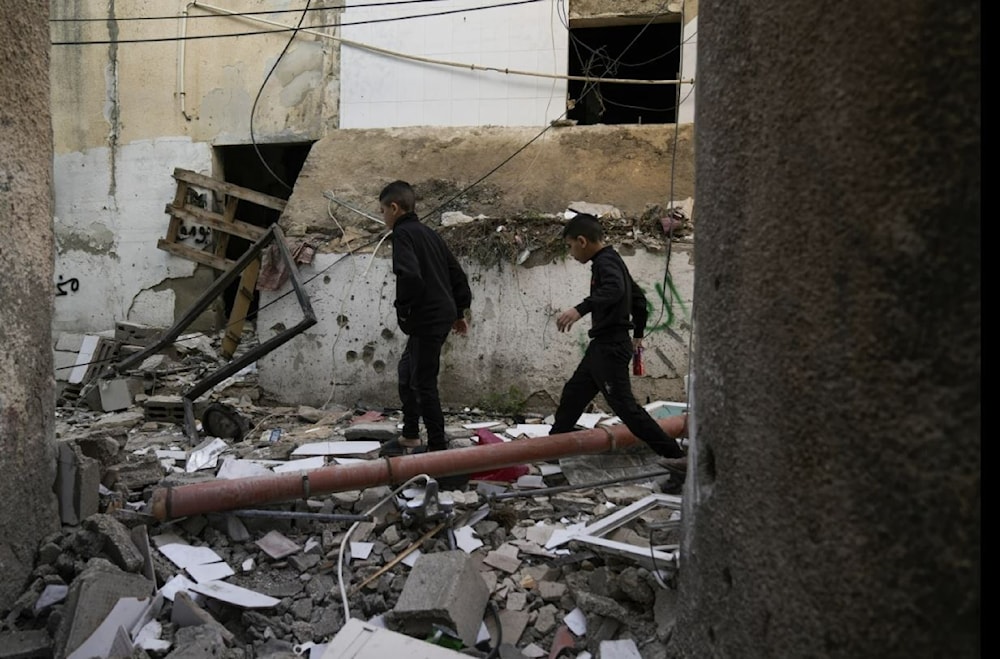 Palestinians walk by a damaged building following an Israeli deadly raid in Jenin refugee camp on November 26.   (AP)