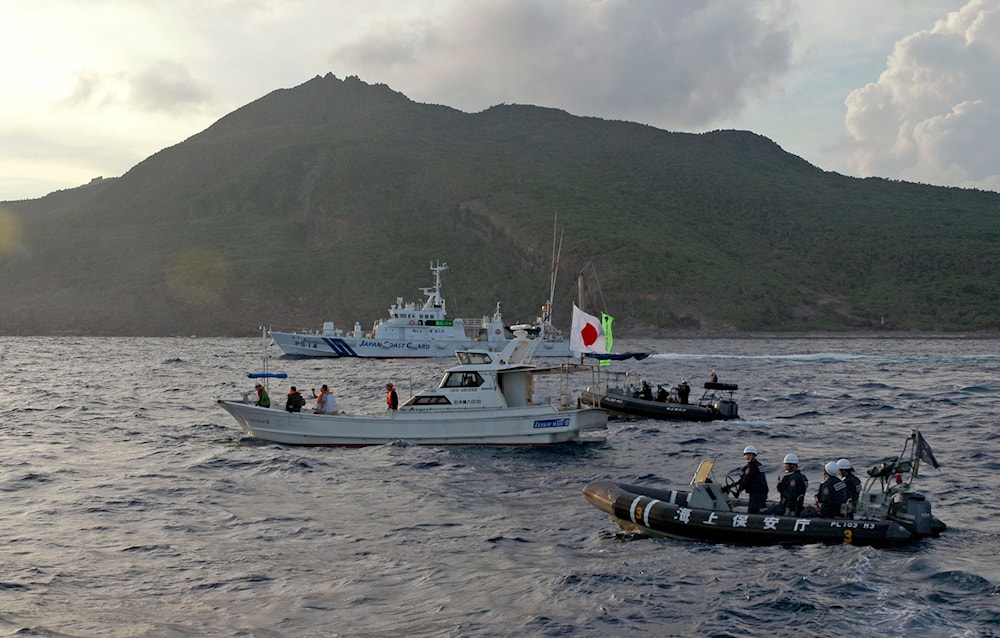 a Japanese Coast Guard boat and vessel sail alongside Japanese activists' fishing boat, not in photo, warning the activists away from a group of disputed islands called Senkaku by Japan and Diaoyu by China on Aug. 18, 2013 (AP)
