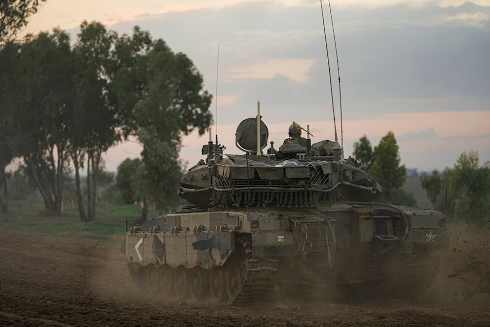 Israeli soldiers move tanks at a staging area near the separation barrier with the Gaza Strip, southern occupied Palestine, November 28, 2023 (AP)