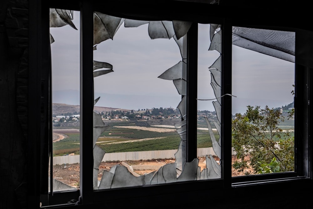 The Israeli settlement of 'Metula', background, is seen through a broken window of a house that was hit by Israeli shelling in Kfar Kila border village with occupied Palestine, south Lebanon, November 25, 2023 (AP)