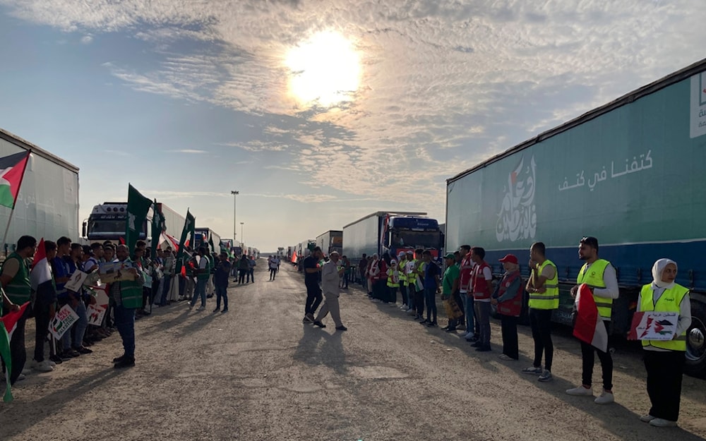Volunteers stand in front of trucks carrying humanitarian aid to Palestinians at the Rafah border crossing between Egypt and Gaza Strip, in Rafah, Egypt, Tuesday, Oct. 31, 2023. (AP Photo/Ahmed Hatem)