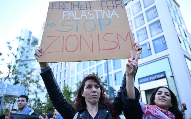 A protester displays a placard calling for the end of Zionism during a pro-Palestinian rally in Frankfurt, Germany on October 14, 2023, amid the ongoing genocide in Gaza. (AFP)