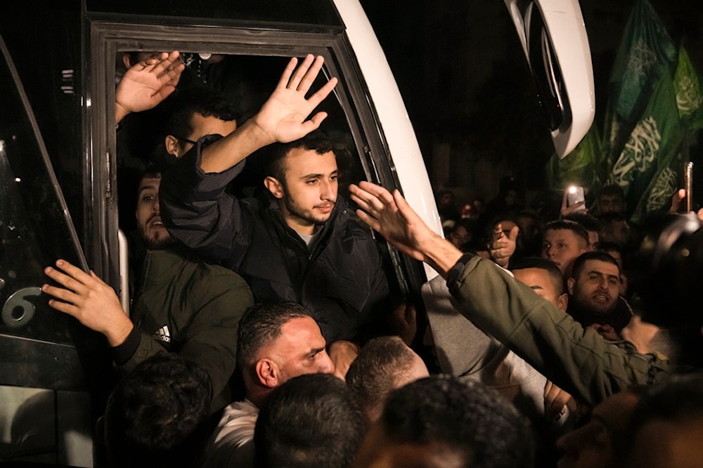 Men wave after being released from Israeli prisons by the Palestinian Resistance in the occupied West Bank town of Ramallah, November 30, 2023 (AP)