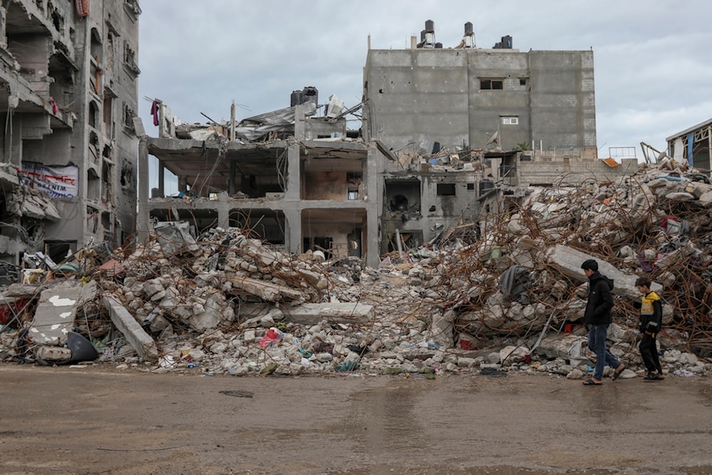 Palestinians walk by a destroyed building in Jebaliya refugee camp, Gaza Strip, Tuesday, Nov. 28, 2023. (AP Photo/Mohammed Hajjar)