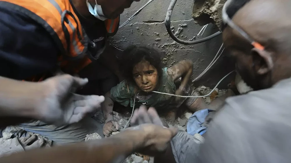 Palestinians try to pull a girl out of the rubble of a building that was destroyed by Israeli air strikes in Jabaliya refugee camp, on 1 November 2023 (AP)