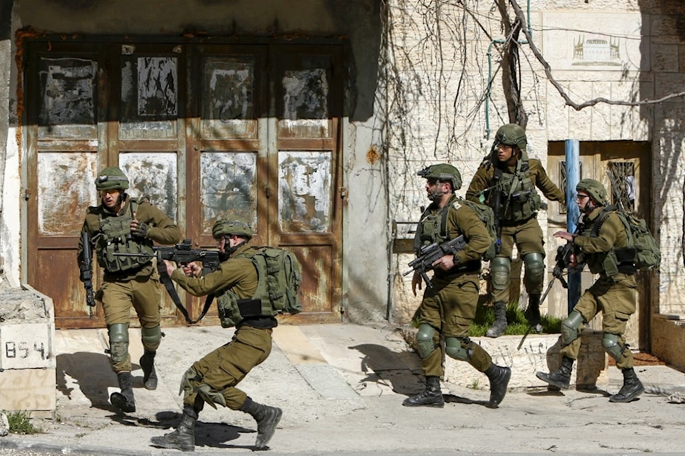 Israeli occupation forces point weapons at Palestinians in the West Bank in 2020 (AFP)