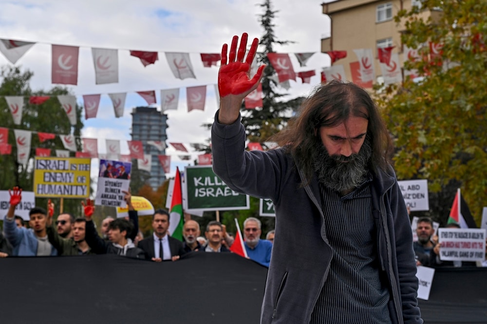 A man raises his hand painted in red during a pro Palestinians protest outside Turkish Foreign Affairs Ministry in Ankara, Turkey, Monday, Nov. 6, 2023. (AP)
