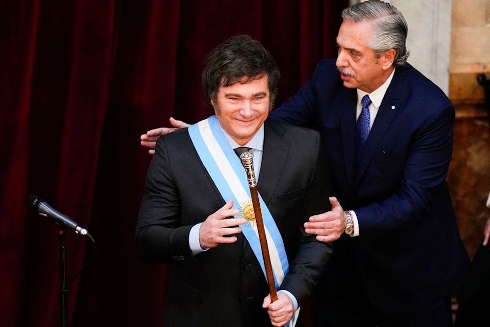 Argentina's outgoing President Alberto Fernandez pats incoming President Javier Milei after handing him the presidential sash at the Congress in Buenos Aires, Argentina, December 10, 2023 (AP)