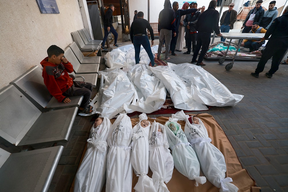 People mourn by the bodies of people killed following Israeli bombardment, including three children from the Harb family, at al-Najjar hospital in Rafah in the southern Gaza Strip on December 12, 2023, amid ongoing battles between 