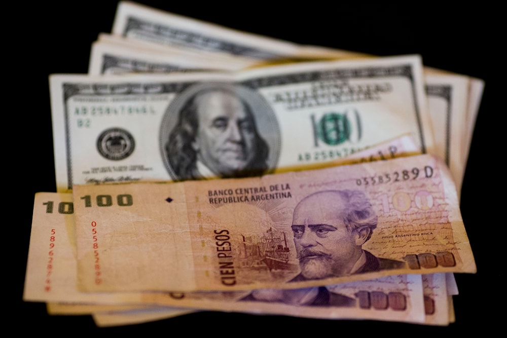 U.S. dollar bills and Argentine pesos are displayed for the photographer on a table at a currency exchange business in Buenos Aires, Argentina, Thursday, Jan. 23, 2014. (AP)