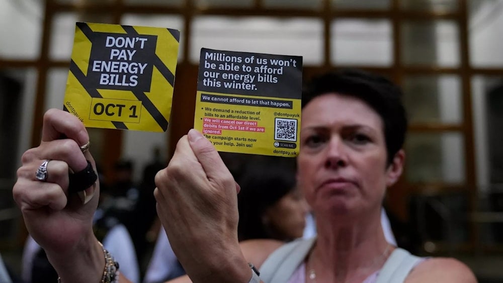 A demonstrator holds up two cards as they protest outside the British energy regulator Ofgem (AP)