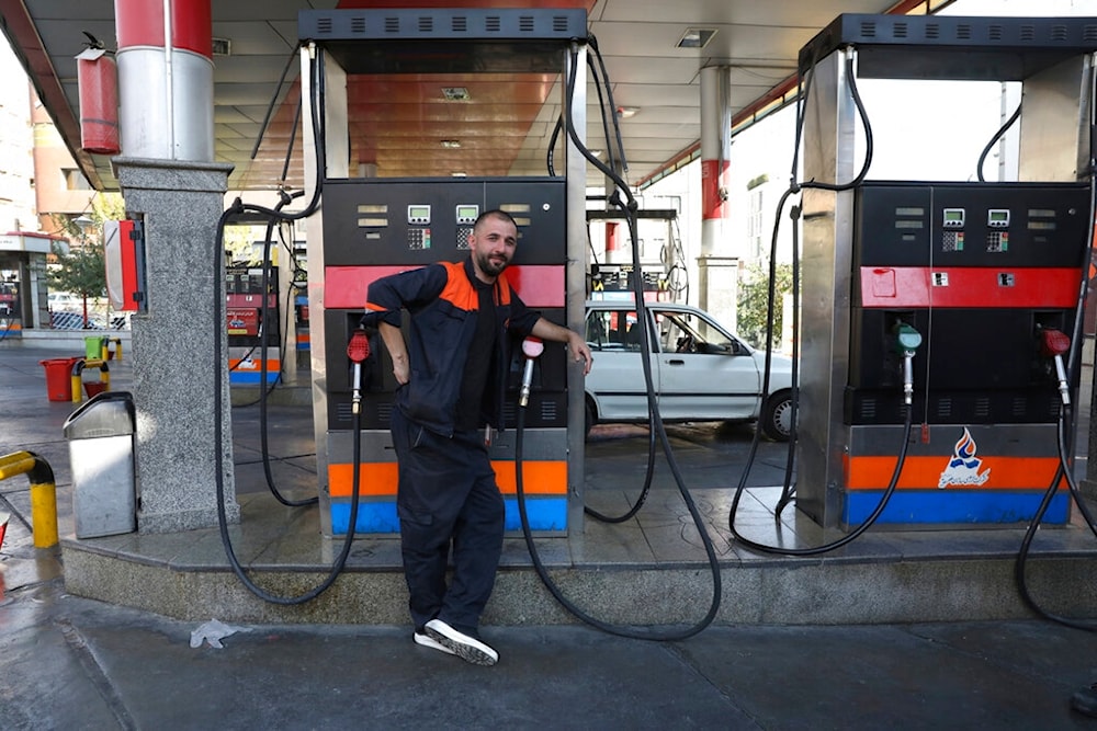 A worker leans against a gasoline pump that has been turned off, at a gas station in Tehran, Iran, Tuesday, Oct. 26, 2021 (AP)