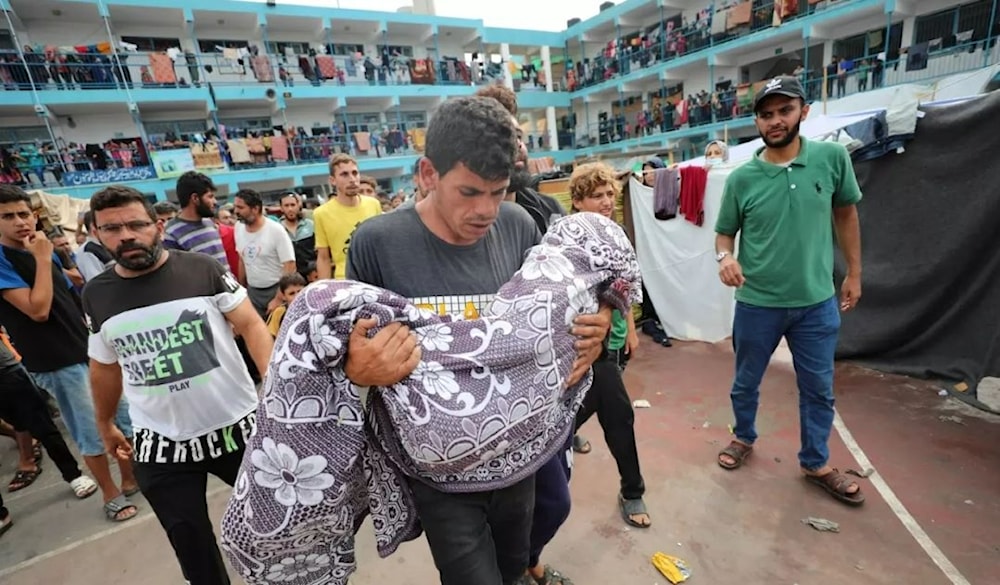 Palestinian father carries his child in the Israeli bombardment of the Gaza Strip during his funeral at a UN-run school in Deir al Balah, Gaza Strip, 27 October 2023 (AP)
