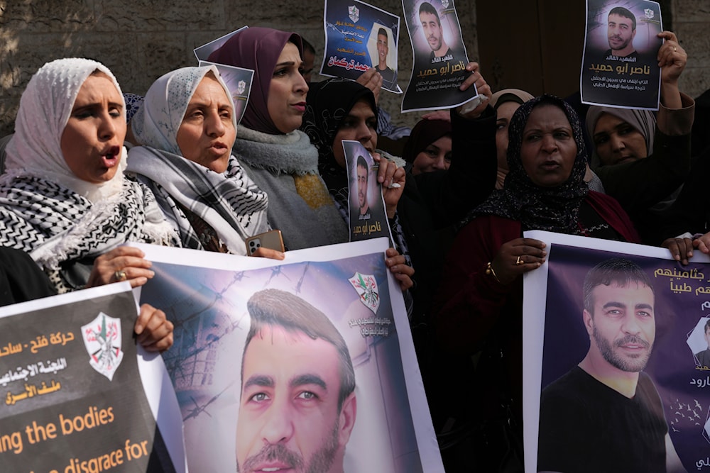 Palestinian women hold posters of Nasser Abu Hamid, a veteran Palestinian prisoner who died from lung cancer in Israeli custody last week, in front of the International Committee of the Red Cross office, in Gaza City, Tuesday, Dec. 27, 2022. (AP)