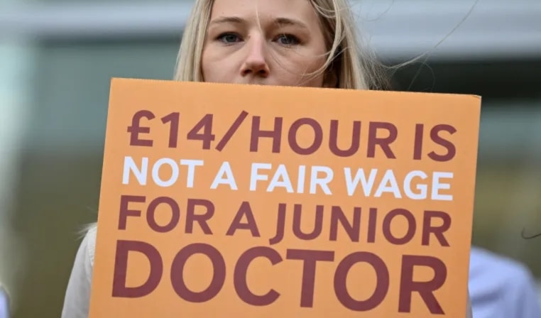 A protestor holding a sign during an NHS doctors walk-out in 2023 (AFP)
