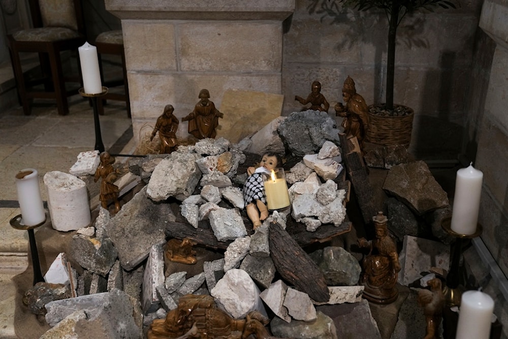 An installation of a scene of the Nativity of Christ with a figure symbolizing baby Jesus lying amid the rubble, in reference to Gaza, inside the Evangelical Lutheran Church in the West Bank town of Beit Lahm, Sunday, Dec. 10, 2023 (AP)