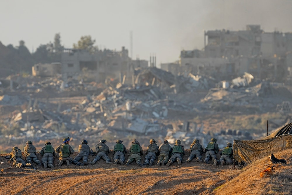 Israeli soldiers take positions near the Gaza Strip border, in southern occupied Palestine, December 11, 2023 (AP)