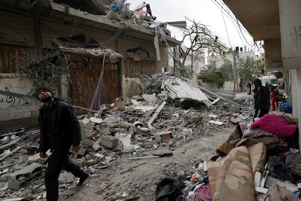 Palestinian citizens look at the residential building of the Khalifa family destroyed in an Israeli strike in Nusseirat refugee camp, central Gaza Strip, Saturday, Dec. 23, 2023 (AP Photo/Adel Hana)