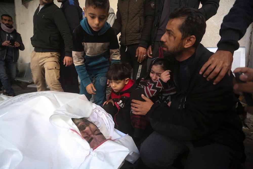 Relatives mourn Adel Zorob, a Palestinian freelance journalist who was killed with his family in the Israeli bombardment of the Gaza Strip outside a morgue in Rafah, occupied Palestine, December 19, 2023 (AP)