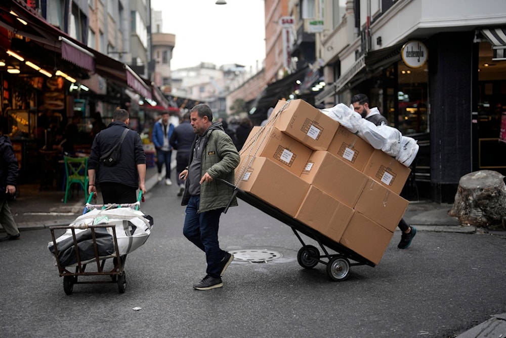 Two men pull trollies with goods in a street market in a commercial district in Istanbul, Turkey, Thursday, Dec. 21, 2023. (AP)