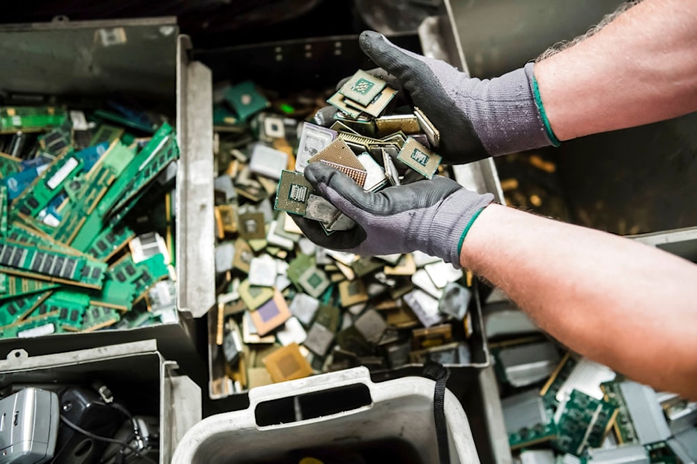A worker handles components of electronic elements at the Out Of Use company warehouse in Beringen, Belgium, July 13, 2018 (AP)