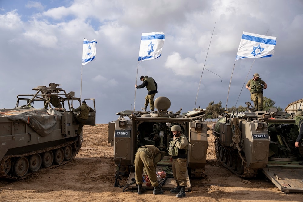Occupation soldiers work on armored military vehicles, in southern Occupied Palestine, on Monday, Nov. 20, 2023 (AP)