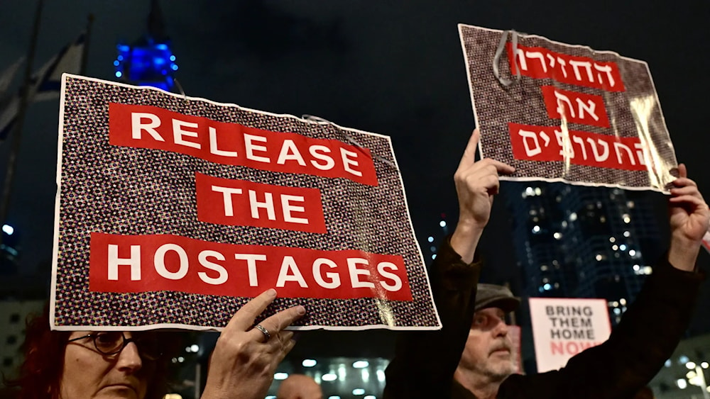 Protesters in 'Tel Aviv' lift placards during a rally for supporters and relatives of Israeli captives held in Gaza. (AFP)