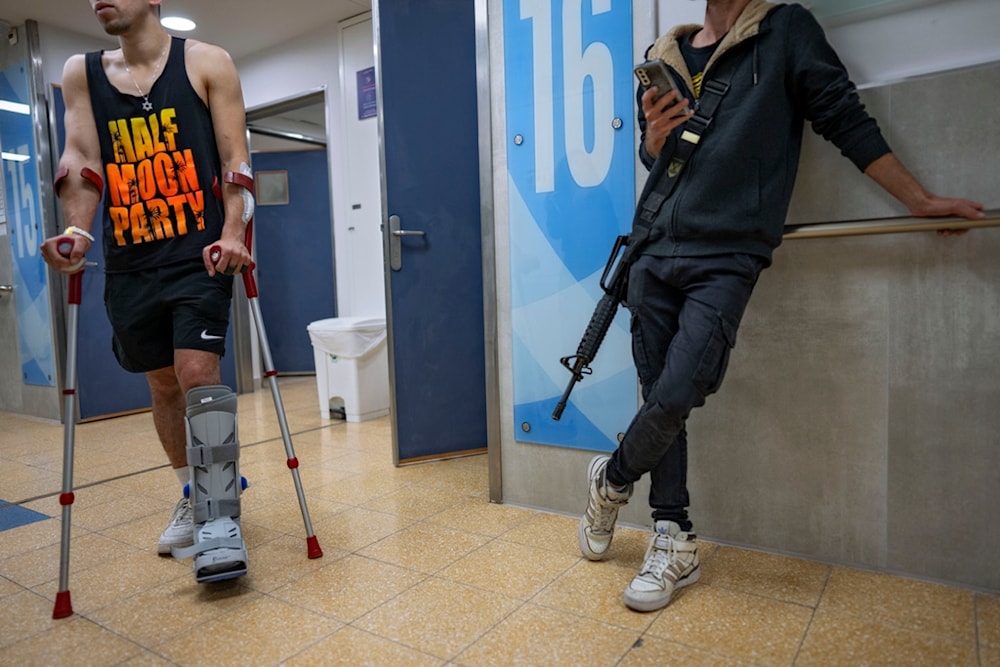 An Israeli soldier wounded in the war on Gaza walks with crutches in the rehabilitation division of Sheba hospital in 'Ramat Gan', occupied Palestine, December 18, 2023 (AP)