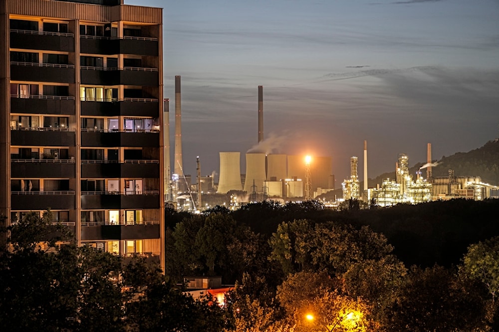 The coal-fired power plant Uniper Scholven and a nearby BP refinery shine in the evening behind illuminated appartments in Gelsenkirchen, Germany, Monday, Oct. 2, 2023 (AP)