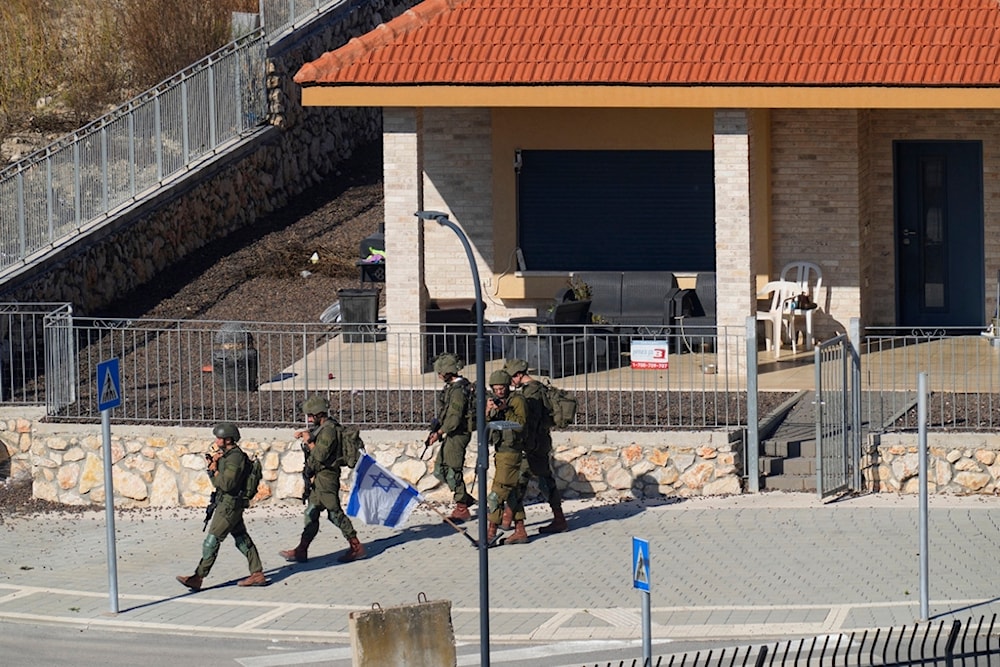 Israeli Occupation Forces are deployed between houses in the Israeli settlement of Metula, as seen from the Lebanese side of the Blue Line in the southern village of Kfar Kila, Friday, Oct. 13, 2023. (AP)