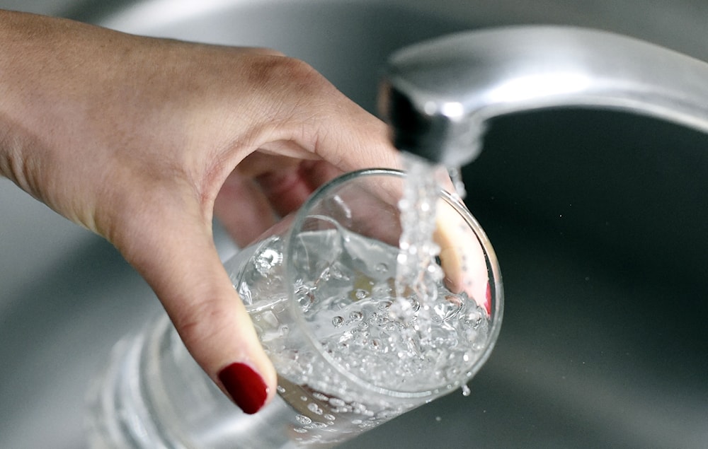 A women drinking water from a tap (AFP via Getty Images)