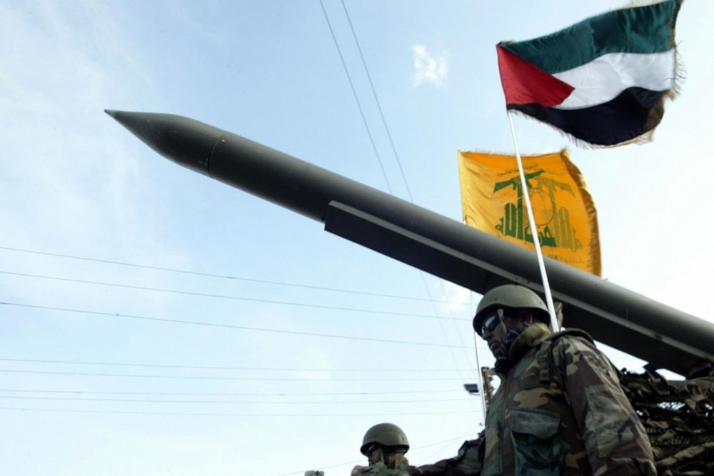 Hezbollah Resistance fighters parade with a missile as the Palestinian (R) and the movement’s (back) flags flutter during an annual parade in the southern city of Nabatieh, Lebanon on January 10, 2009 (AFP)