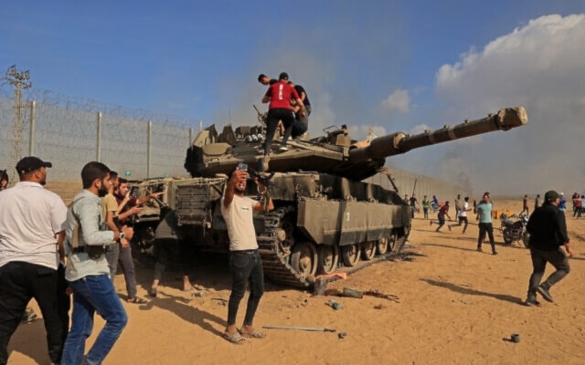 Palestinians take control of an Israeli tank after crossing the occupied Palestinian territory from Khan Younis in the southern Gaza Strip on October 7, 2023. (AFP)