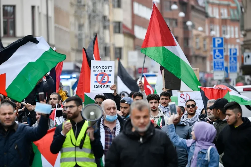 People holding placards and Palestinian flags march in solidarity with the Palestinian people amid the ongoing conflict with Israel, during a demonstration in Malmo, Sweden, on 15 May, 2021 (AFP)