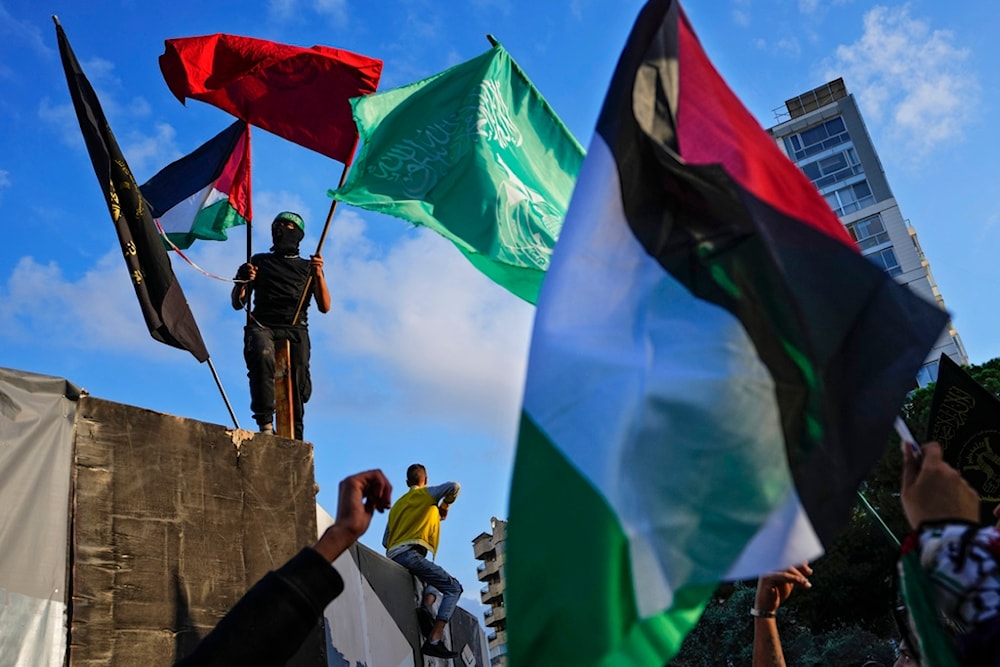 A Palestinian man holds a Palestinian and Hamas flags as others chant slogans against Britain, taking part in a protest near of the British embassy in Beirut, in solidarity with the Palestinian people in Gaza, Tuesday, Nov. 14, 2023. (AP)